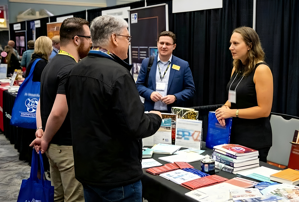 Sponsors talking to conference attendees at booth