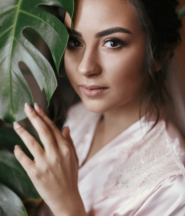 gorgeous bride portrait with monstera leaf. beautiful woman getting ready for wedding, holding green leaf and posing. skin care and make-up. sensual moment